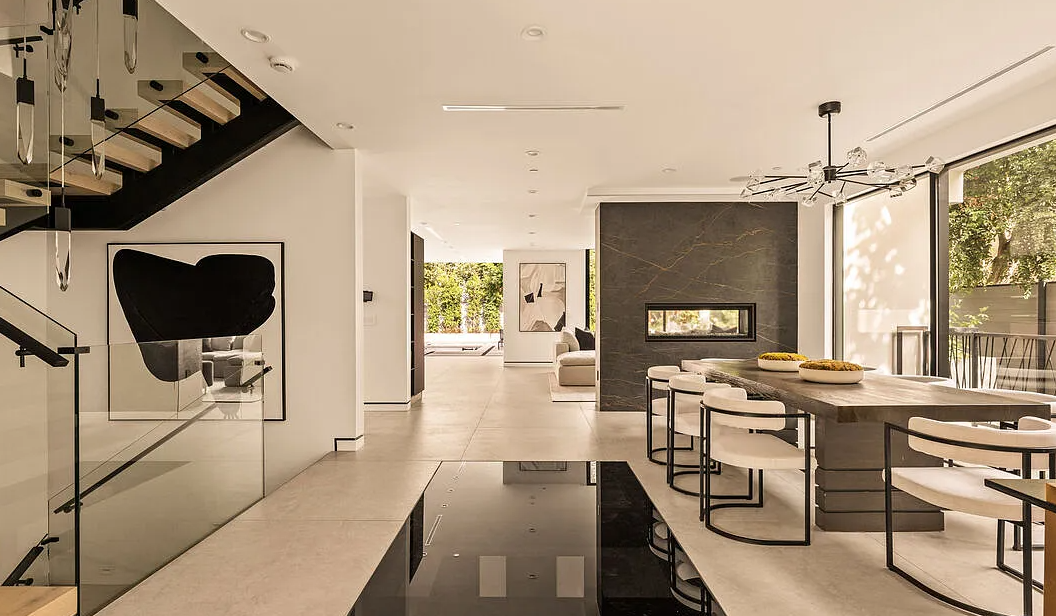 The stair, the dining room and a double-sided stone fireplace, with the garden beyond, La Jolla North in West Hollywood by Apel Design