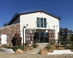 Apel Design: the studio office, a white barn-style building with a stone base and a carved stone head sculpture by the entry