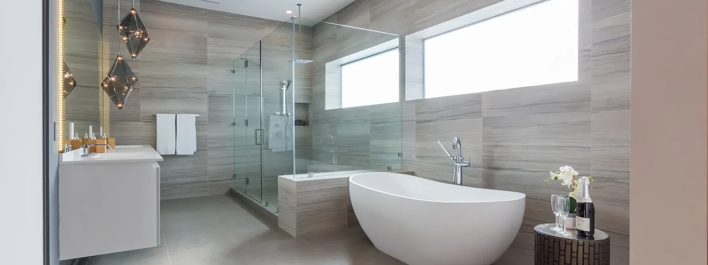 Primary bath with a freestanding tub, faceted glass pendants and stone walls in long horizontal bands, an interior by Apel Design