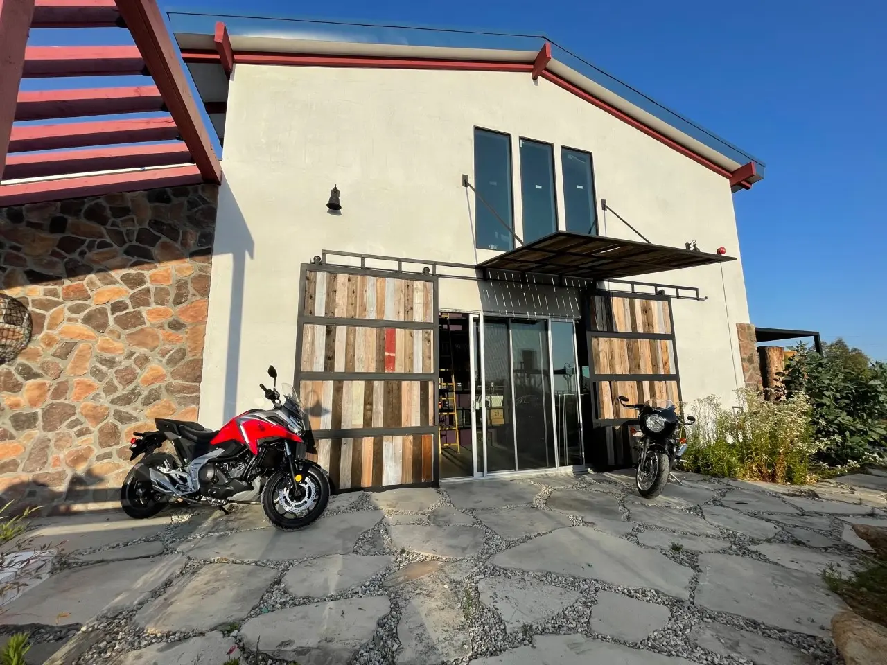 Exterior of the Apel Design studio, with reclaimed wood doors and a stone base