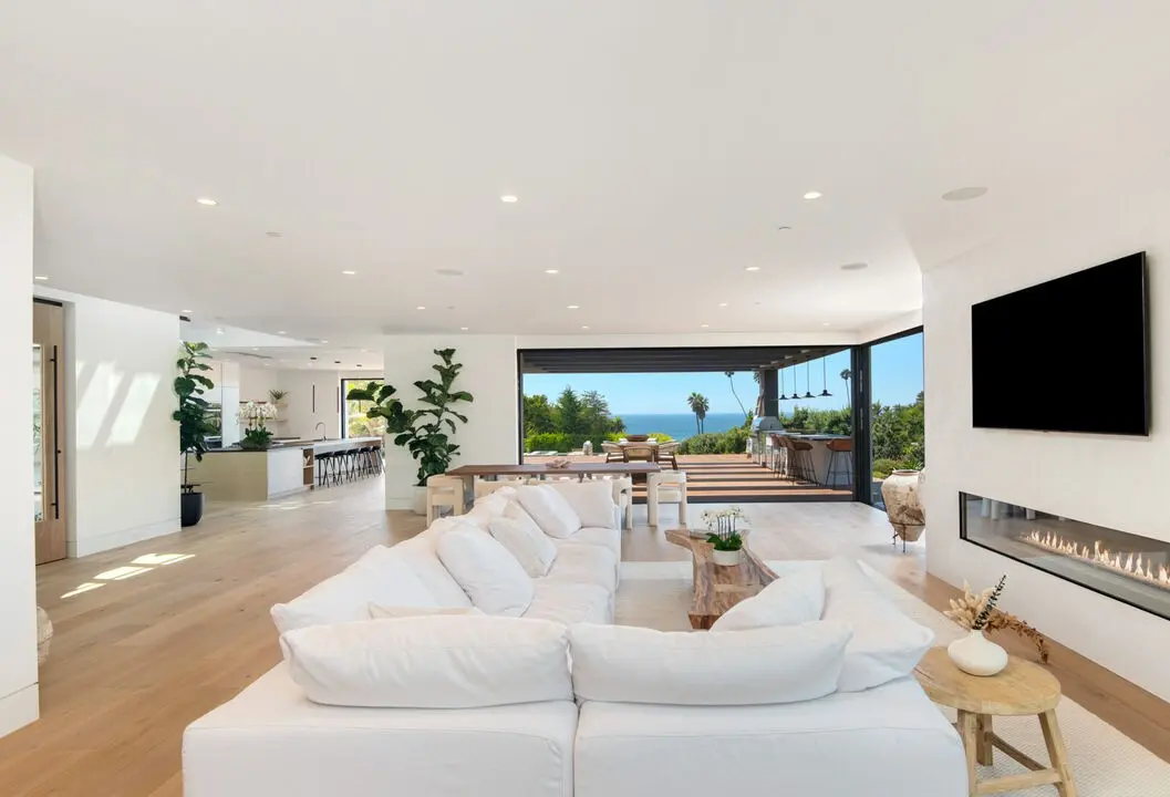 White living room with a linear fireplace and an ocean view, an interior by Apel Design