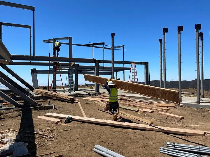 Carpenter carrying sheathing through the steel frame at The Aviator