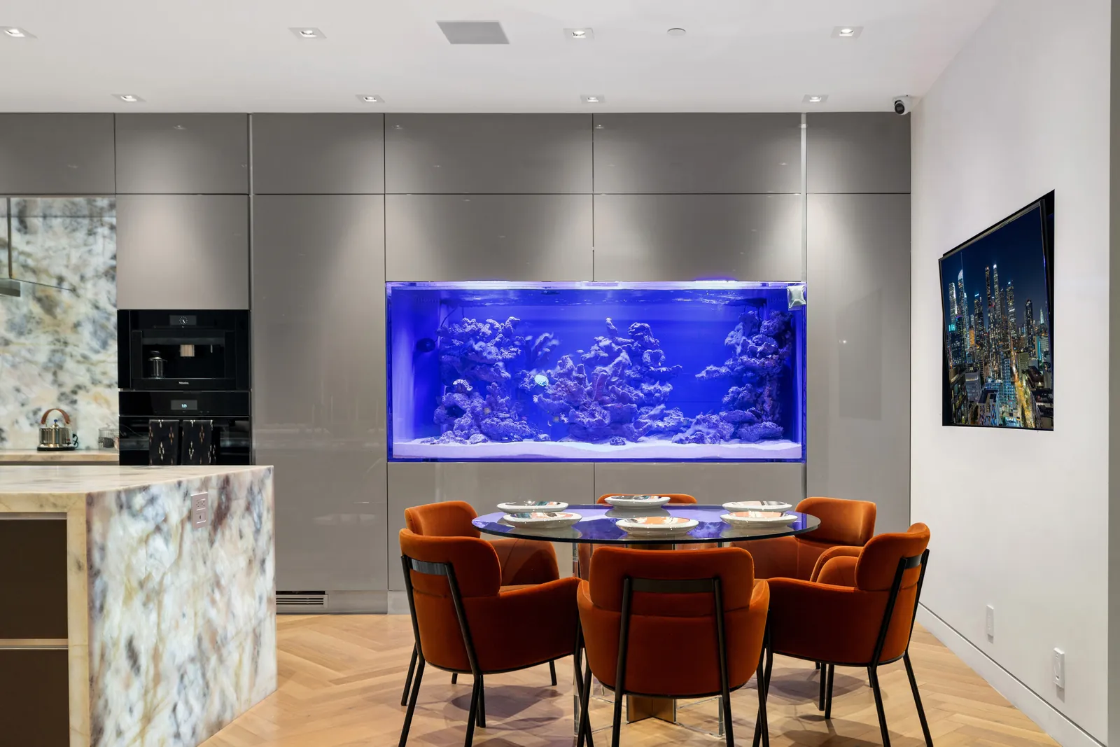 Kitchen and dining interior with a built-in aquarium wall, designed by Apel Design