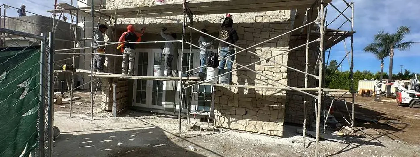 Masons setting stone veneer from scaffolding at The Blue