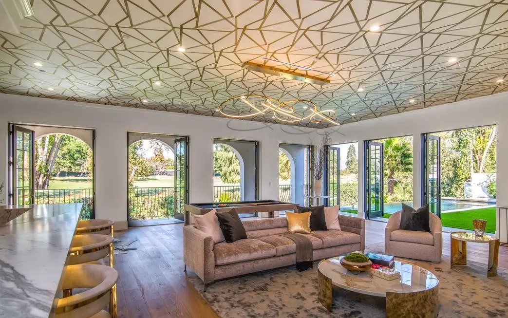 Living room under a geometric gold ceiling with arched glass doors, an interior by Apel Design