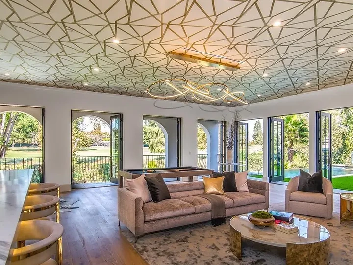 A living room under a geometric patterned ceiling, with arched glass doors to the garden, an interior by Apel Design