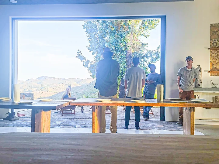 A crew meal at a long table with the hills beyond