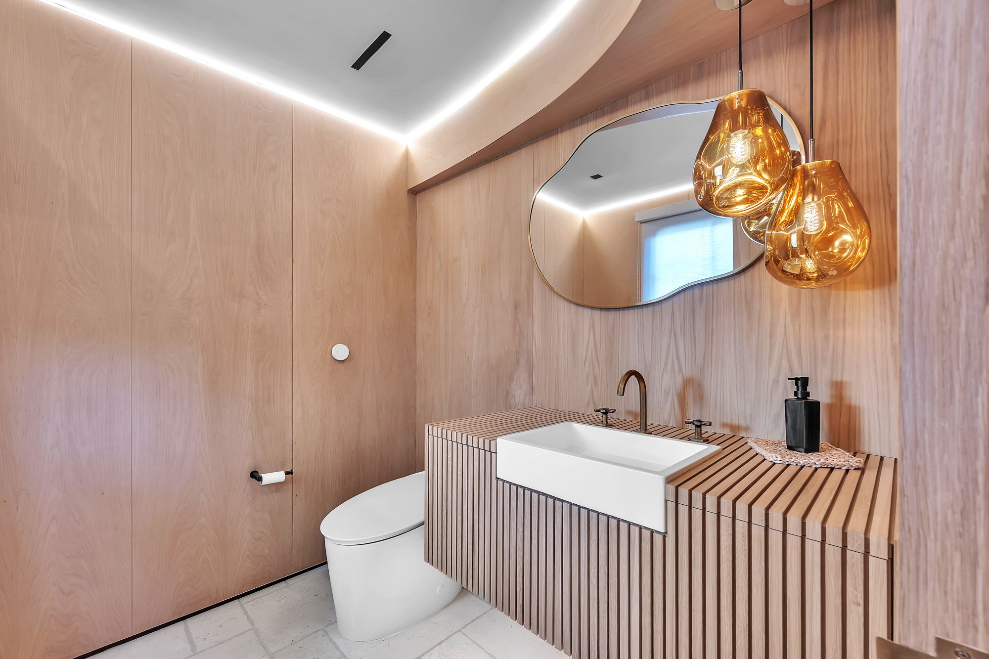 A powder room lined in timber under amber glass pendants, Merritt Estate in Malibu by Apel Design