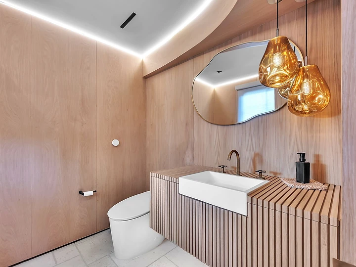 Powder room lined in timber under amber glass pendants, at Merritt Estate in Malibu, by Apel Design