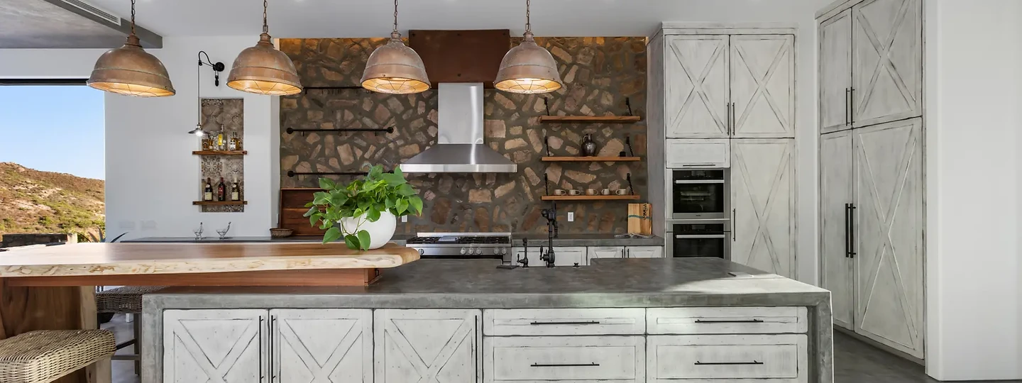 Kitchen island in weathered white cabinetry under copper pendants, at Maliview in the Malibu Mountains, by Apel Design