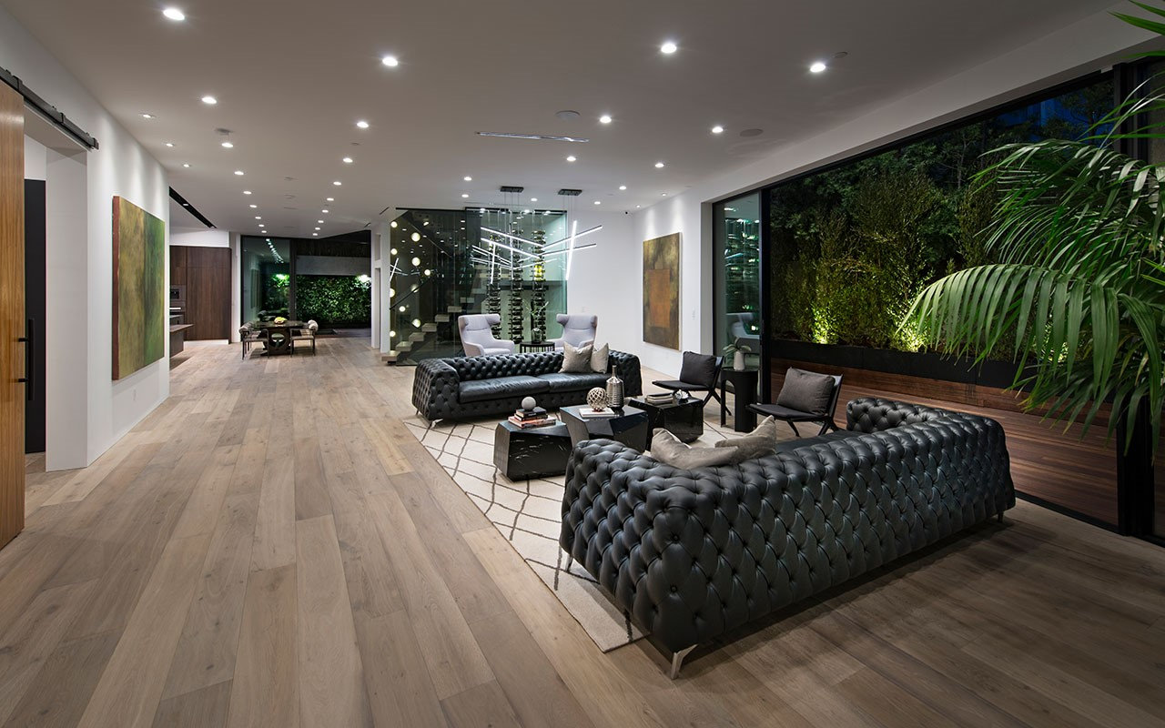 Living room at Shoreham opening to the planted terrace at night, by Apel Design