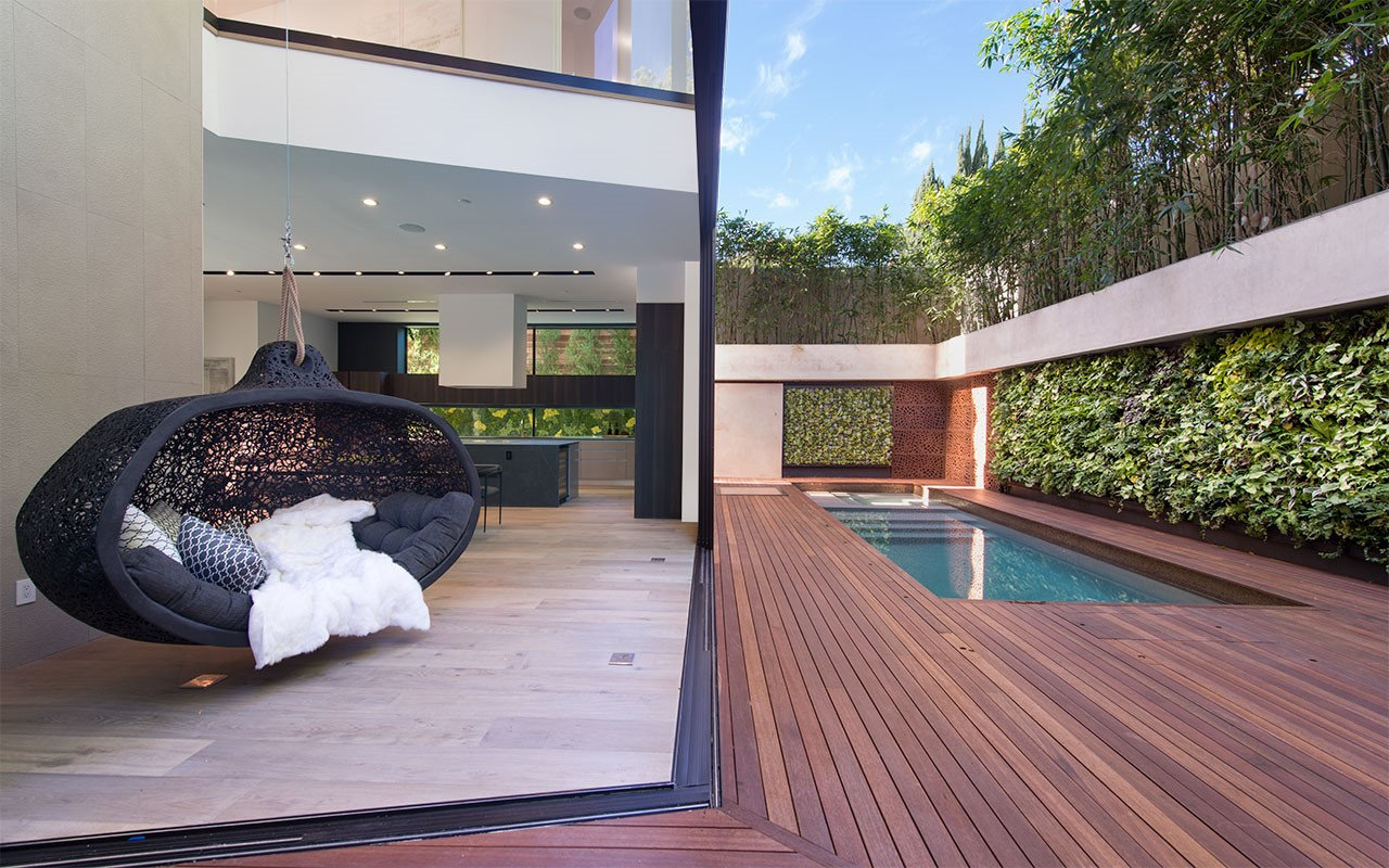 Hanging chair at Shoreham where the glass wall opens to the pool deck, by Apel Design