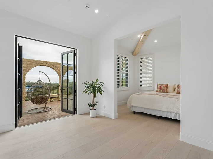 Bedroom at Oya with French doors open to a terrace and a hanging chair