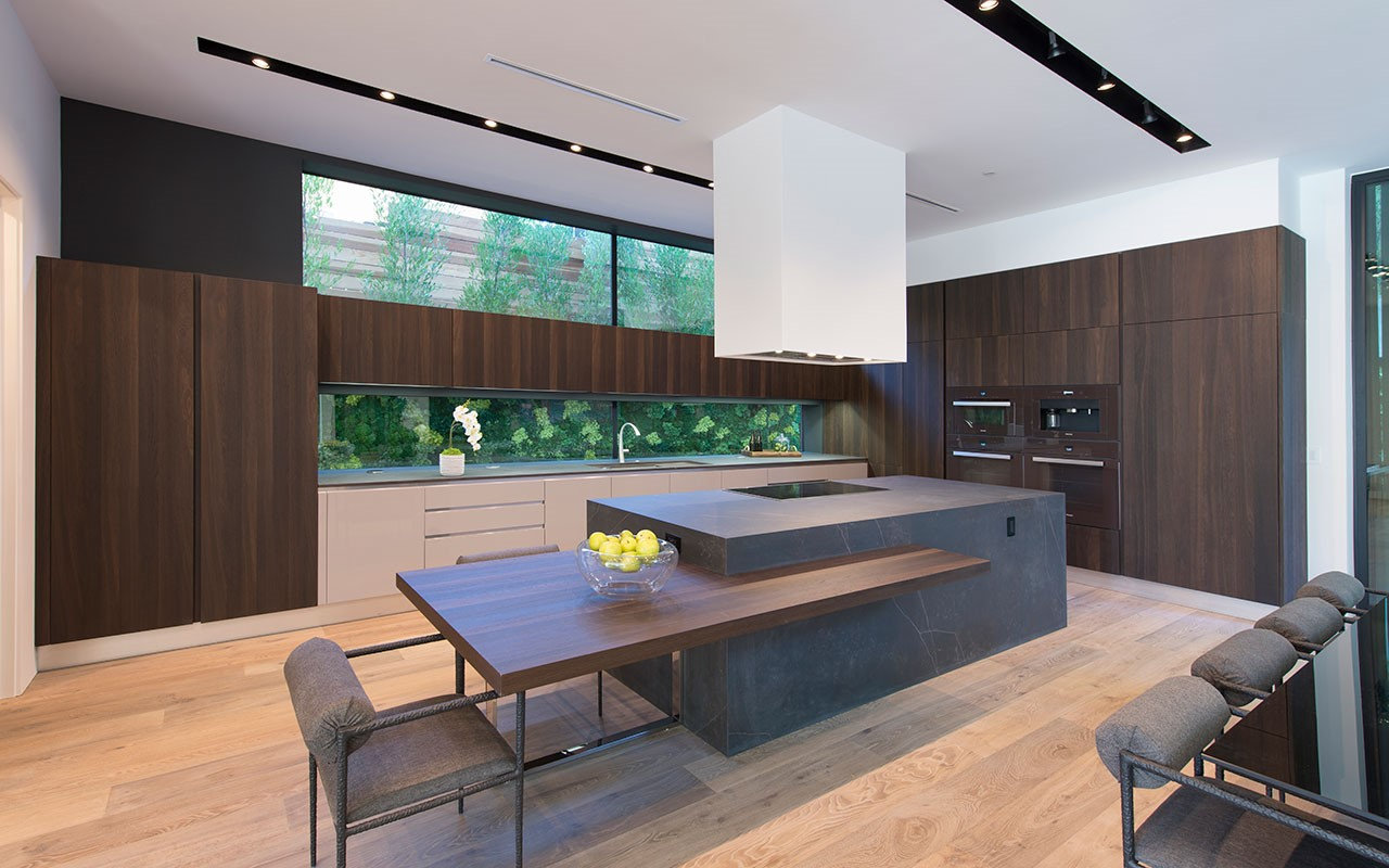 Kitchen at Shoreham with stone island, cantilevered wood table and garden window, by Apel Design