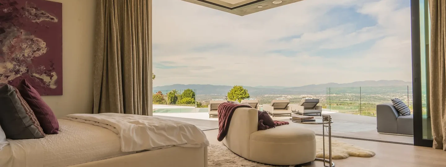 A bedroom with its glass corner open to a terrace and a wide valley view, an interior by Apel Design