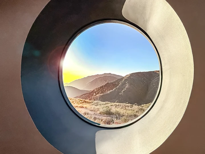 A round window set in a deep curved reveal frames the mountains, at The Aviator in Malibu, by Apel Design