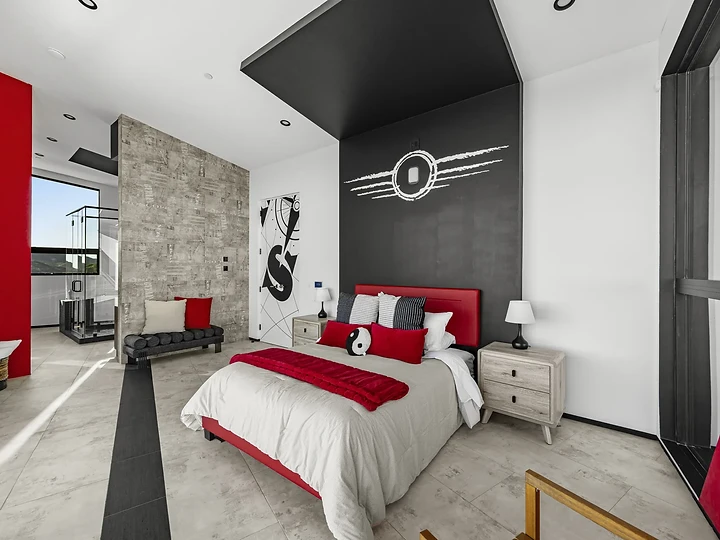 A red bed under a dark canopy wall bearing a winged emblem, at The Aviator in Malibu, by Apel Design