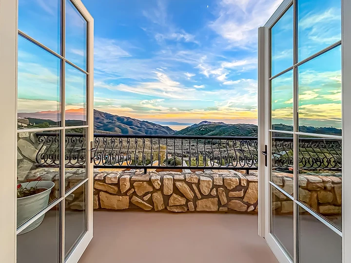 White French doors open to an iron-railed balcony and a mountain view, at Mintcello in Malibu, by Apel Design