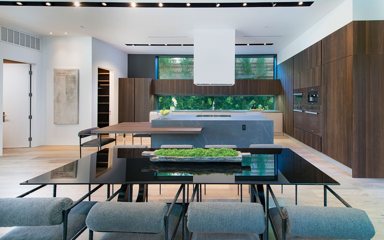 Black glass dining table at Shoreham with the kitchen beyond, by Apel Design