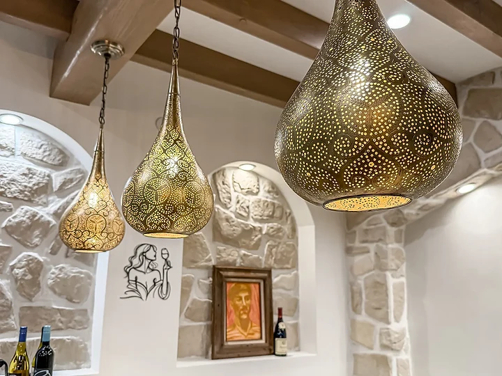 Pierced metal pendants above a stone wall at Mintcello