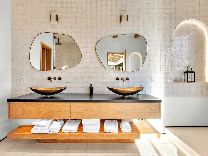 Twin vessel basins under glazed tile and a lit arched niche, at Merritt Estate in Malibu, by Apel Design