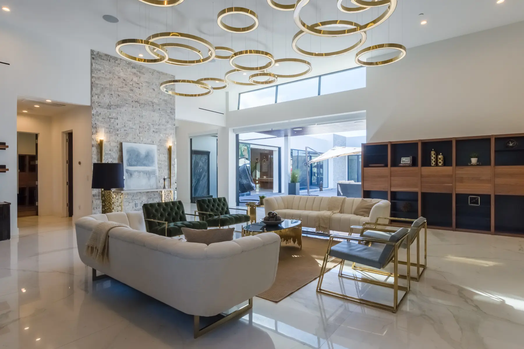 Double-height living room under a cluster of gold ring chandeliers, an interior by Apel Design