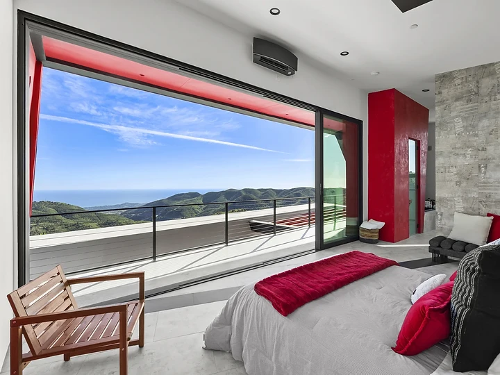 A bed facing a wide opening onto a terrace and the coast, at The Aviator in Malibu, by Apel Design