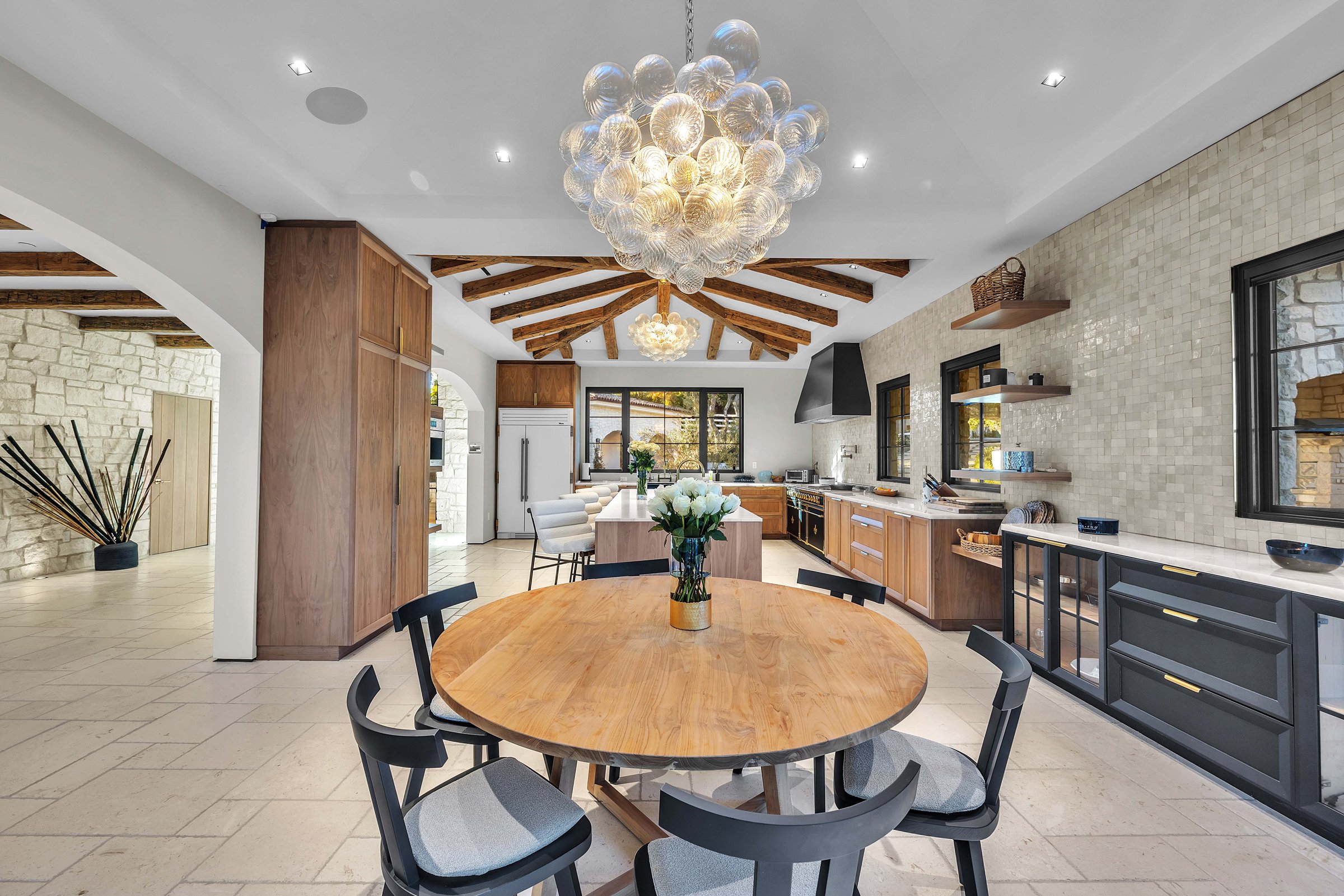 The breakfast table under a glass pendant, with the kitchen beyond, Merritt Estate in Malibu by Apel Design