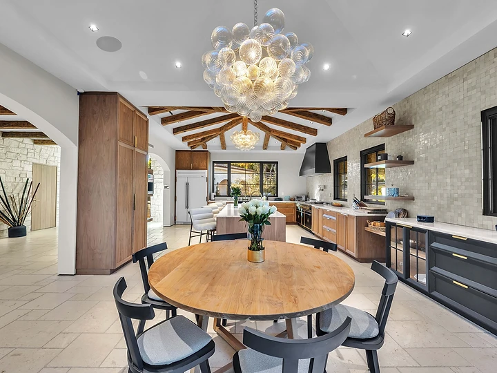 Breakfast table under a glass pendant with the kitchen beyond, at Merritt Estate in Malibu, by Apel Design