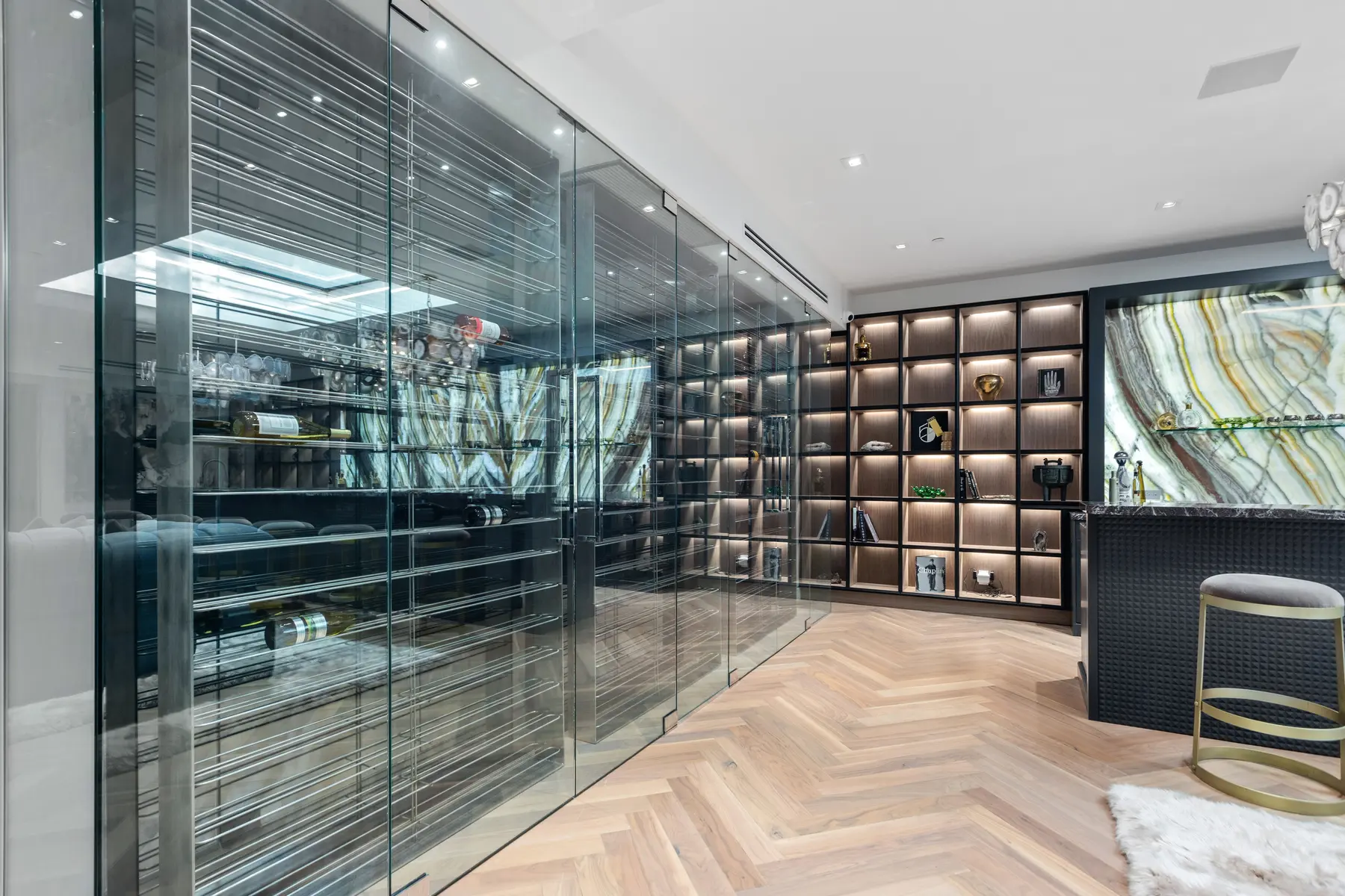 Lit shelving beside a glass-enclosed wine wall, an interior by Apel Design