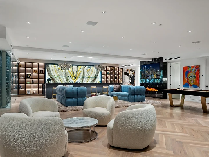 Round white lounge chairs around a stone table, with a billiard table beyond, an interior by Apel Design