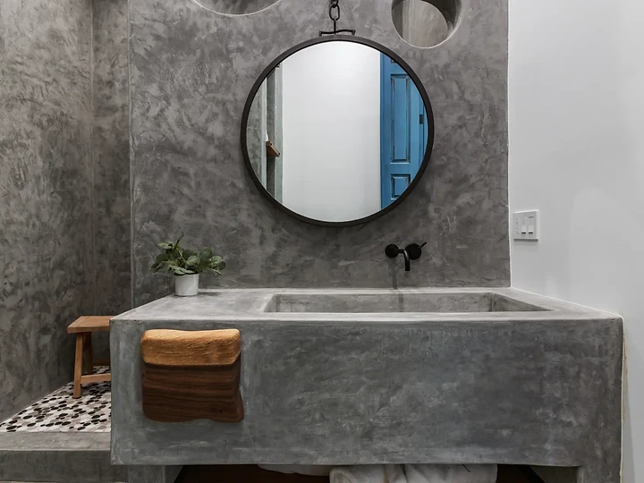 Concrete vanity and round mirror at Maliview