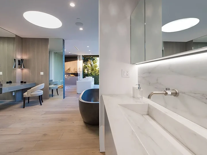 A stone trough basin under a mirror with a hidden light strip, an interior by Apel Design