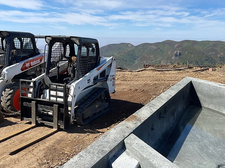 Concrete pool shell and skid loader during sitework at The Aviator