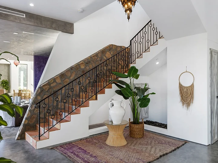 A stair with a stone-clad underside and a patterned iron rail, at Maliview in the Malibu Mountains, by Apel Design