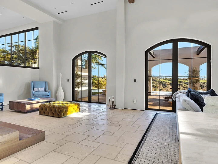 Arched steel-framed doors open the living room to the loggia, at Merritt Estate in Malibu, by Apel Design