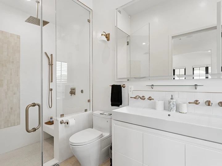 Primary bathroom at Oya with a glass shower, white vanity and brass fittings