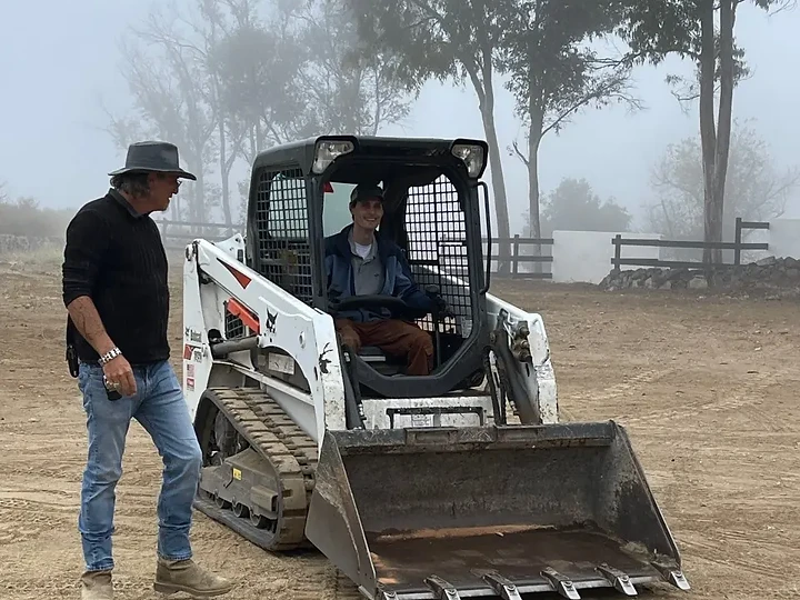 Operating a skid loader on a foggy morning at the studio grounds