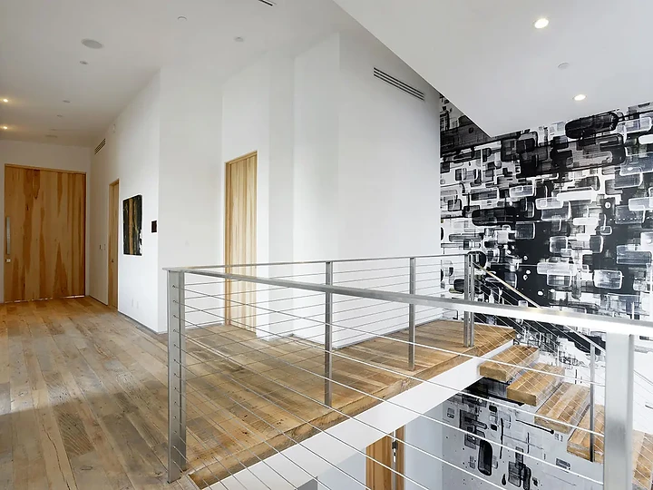 An upper hall with cable rails above a timber stair and a graphic wall, an interior by Apel Design