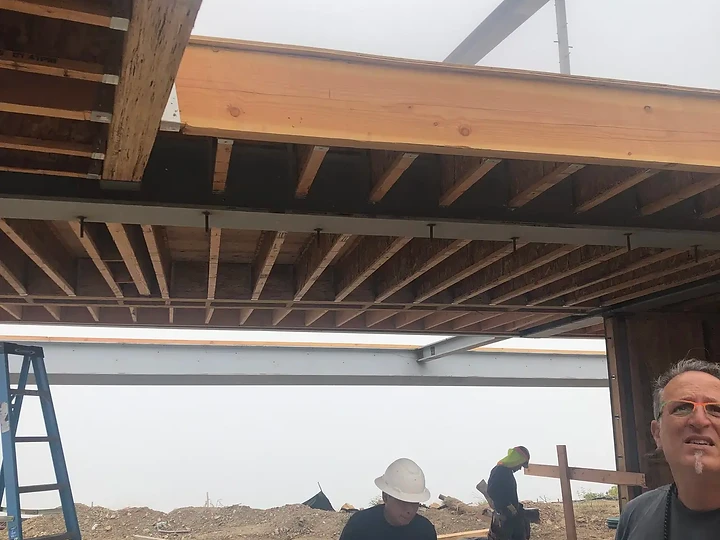 Crew working beneath the steel and timber structure of an Apel Design project