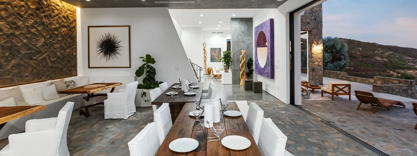 Timber dining table under a textured relief wall, open to the hills, at Maliview in the Malibu Mountains, by Apel Design