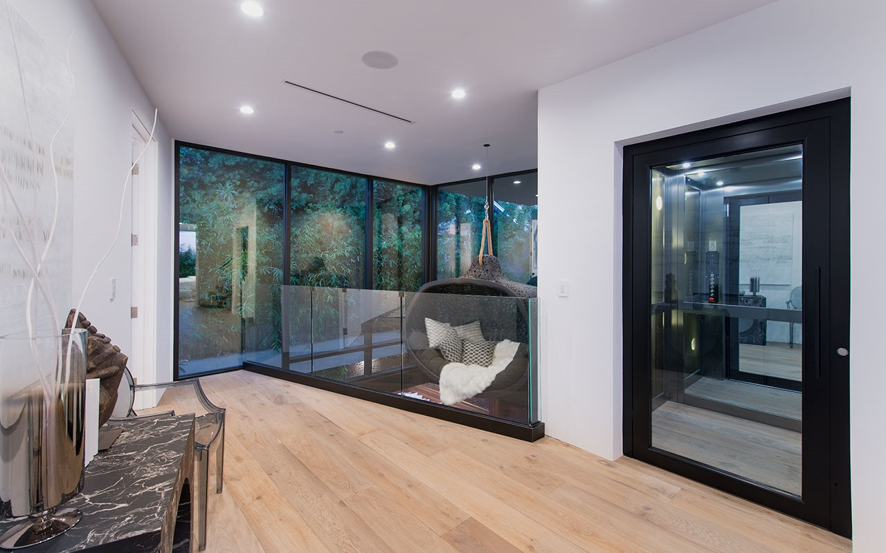 Landing at Shoreham with glass elevator, glass rail and hanging chair, by Apel Design