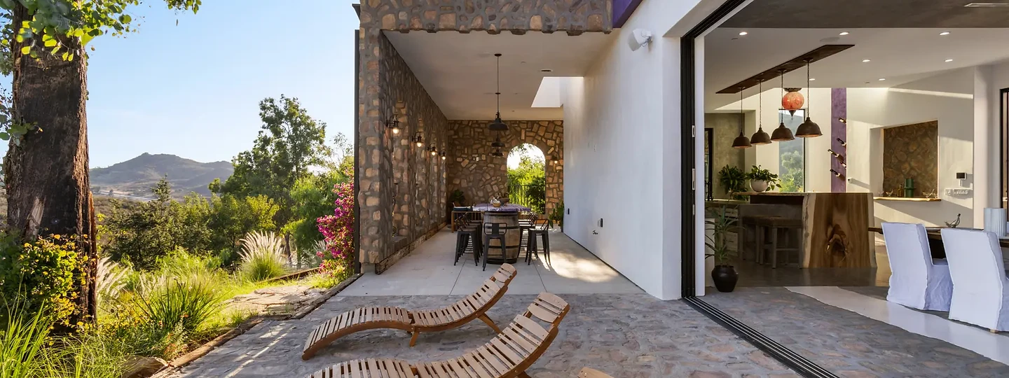Timber loungers on a stone terrace, open to the kitchen, at Maliview in the Malibu Mountains, by Apel Design