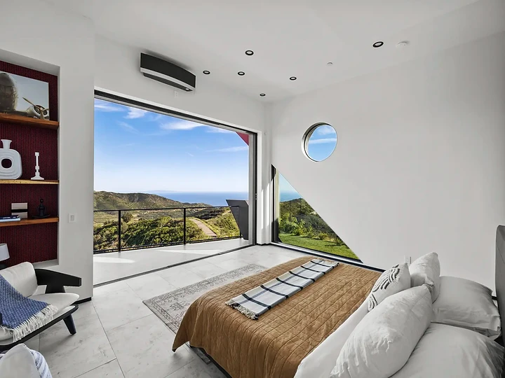 A porthole window, niche shelving and glass opening to green hills, at The Aviator in Malibu, by Apel Design