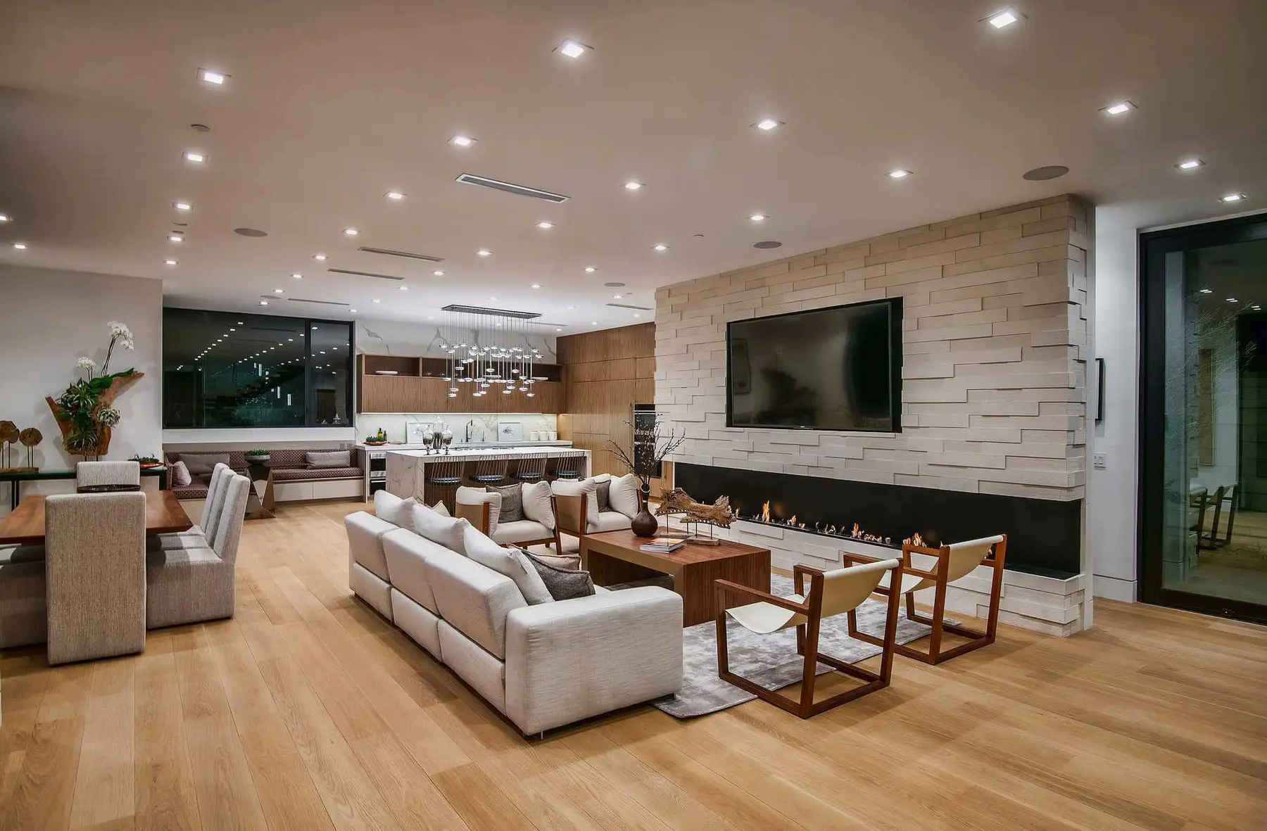 Long living room with a stone media wall and a linear fireplace, an interior by Apel Design