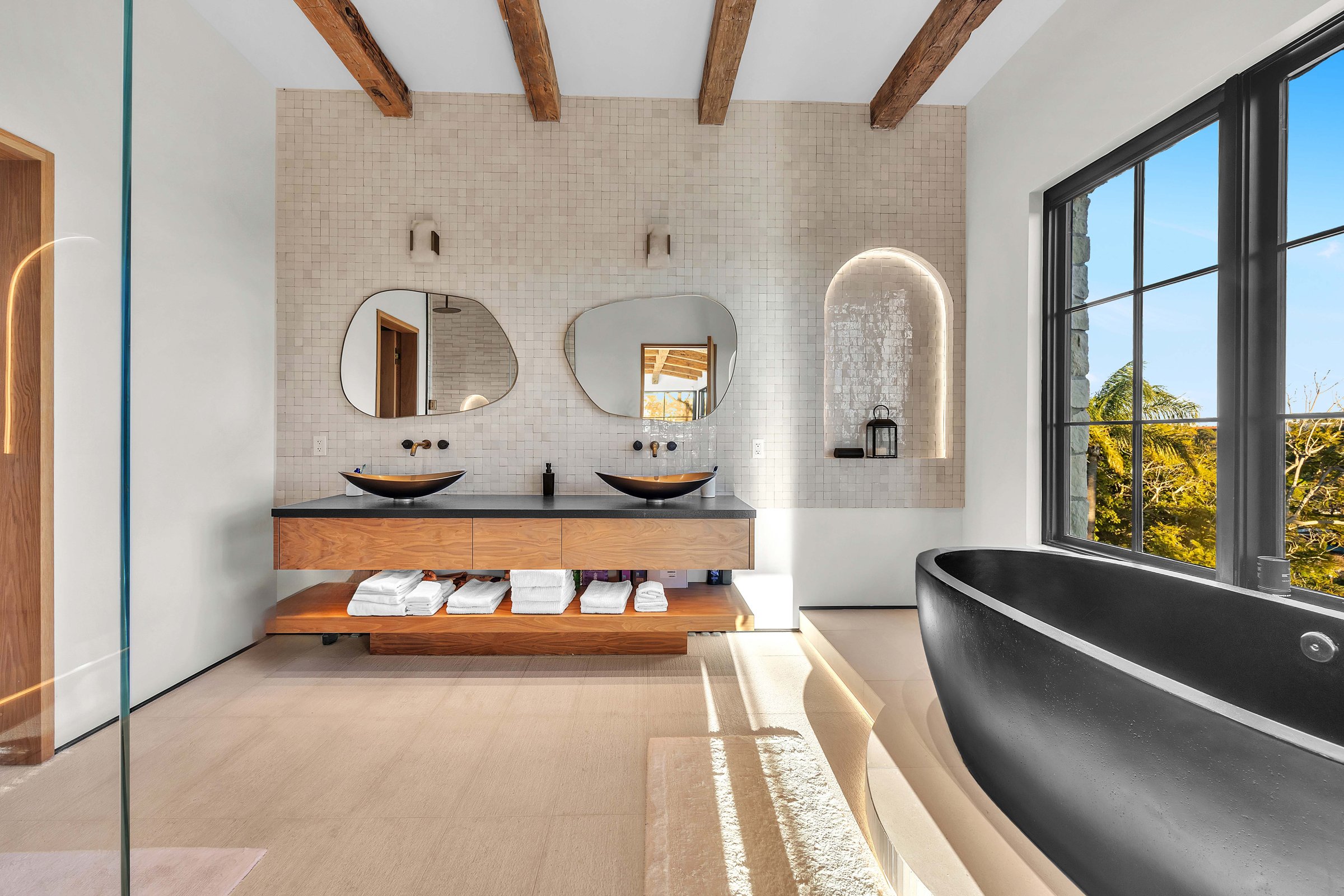 The primary bath, with vessel basins on a floating timber vanity and a black freestanding tub, Merritt Estate in Malibu by Apel Design