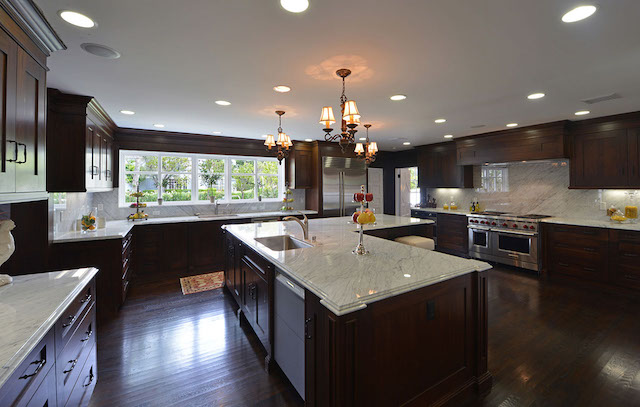 Kitchen at June in dark timber and marble, planned around two islands, by Apel Design