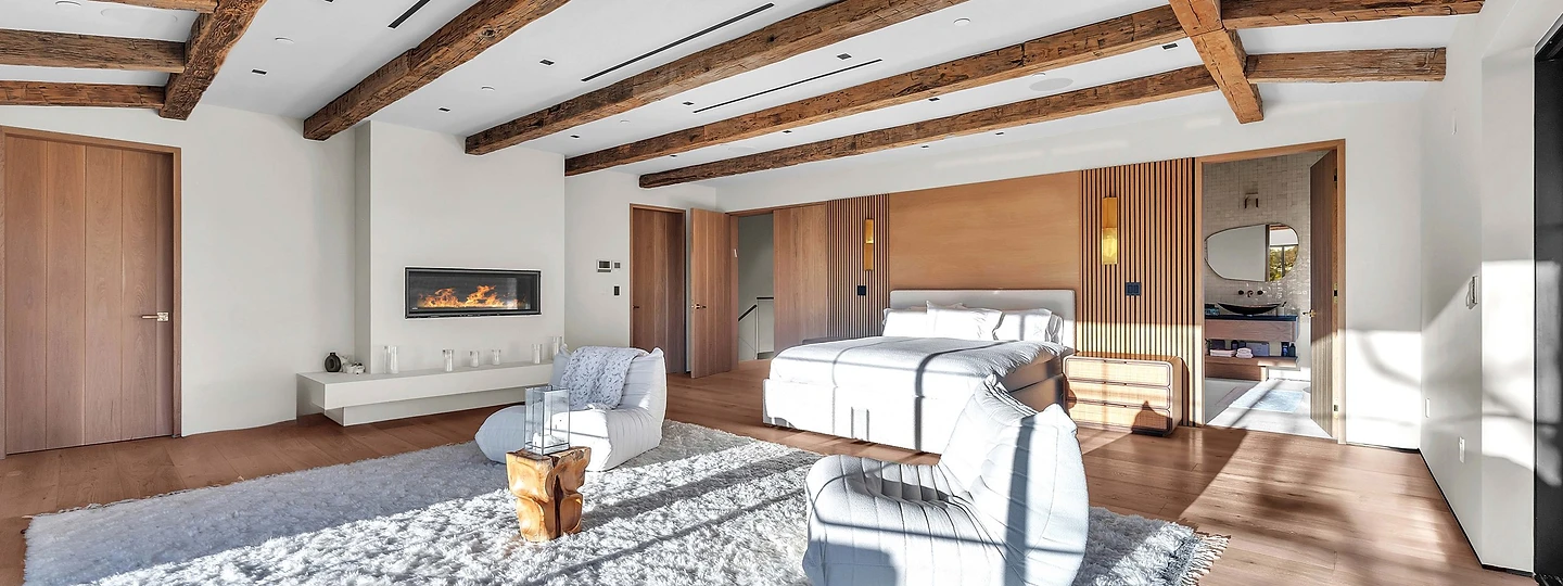 A sitting area and linear fireplace under timber beams, at Merritt Estate in Malibu, by Apel Design