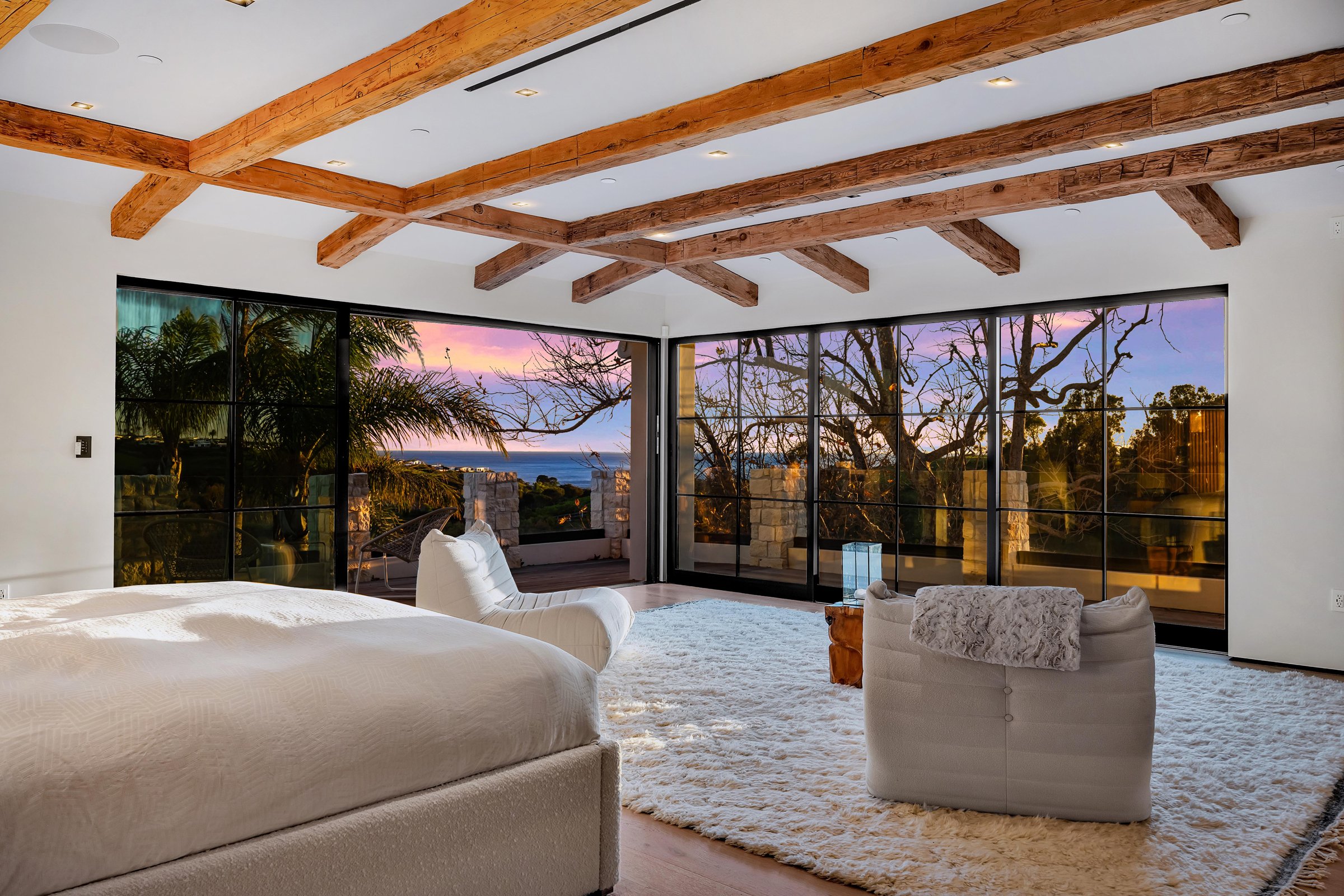 Primary suite at dusk with corner glass facing the ocean, at Merritt Estate in Malibu, by Apel Design