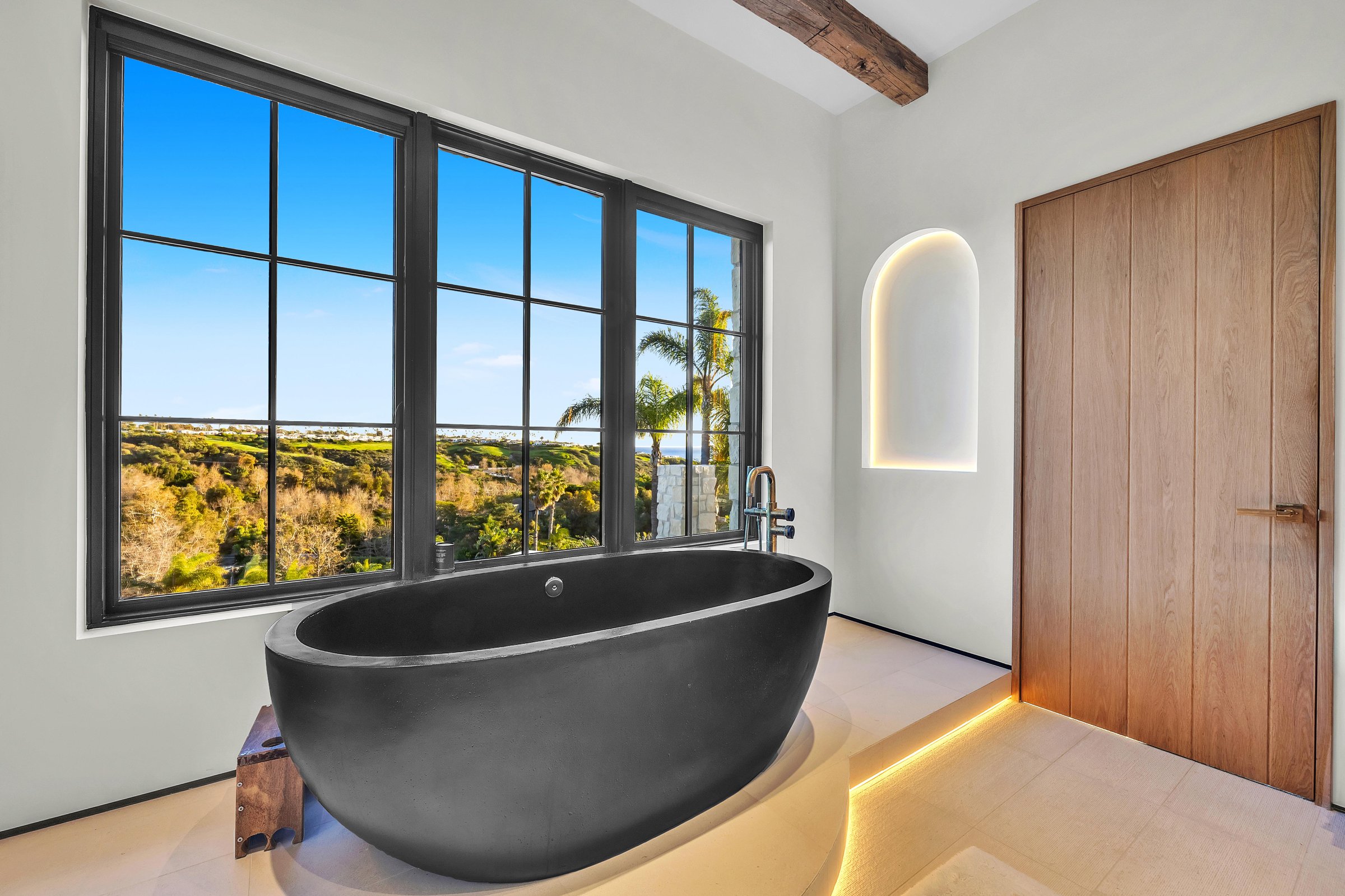 A black freestanding tub set against the window in the primary bath, Merritt Estate in Malibu by Apel Design